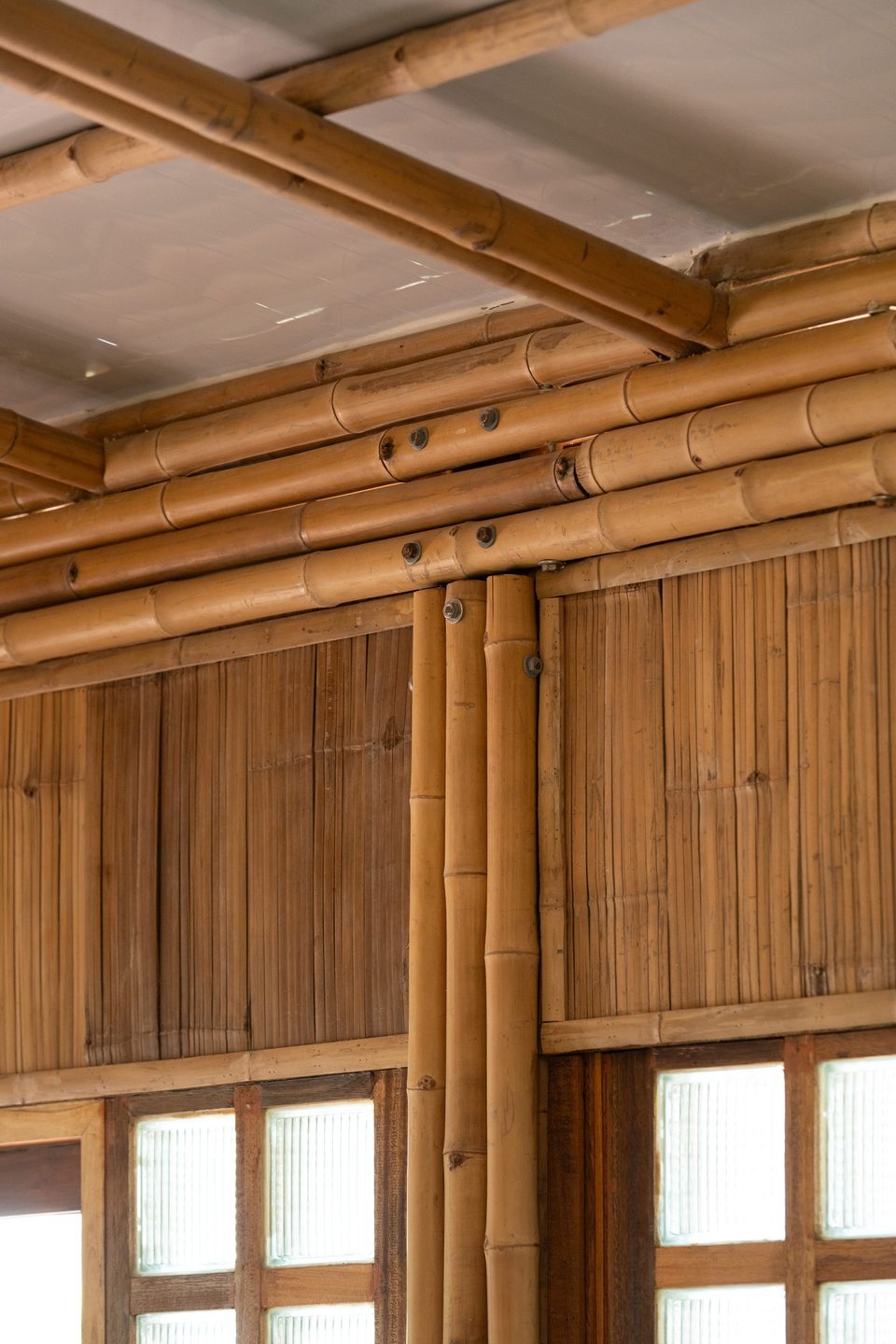 Bolted bamboo beams meeting a bamboo-clad wall inside the shop