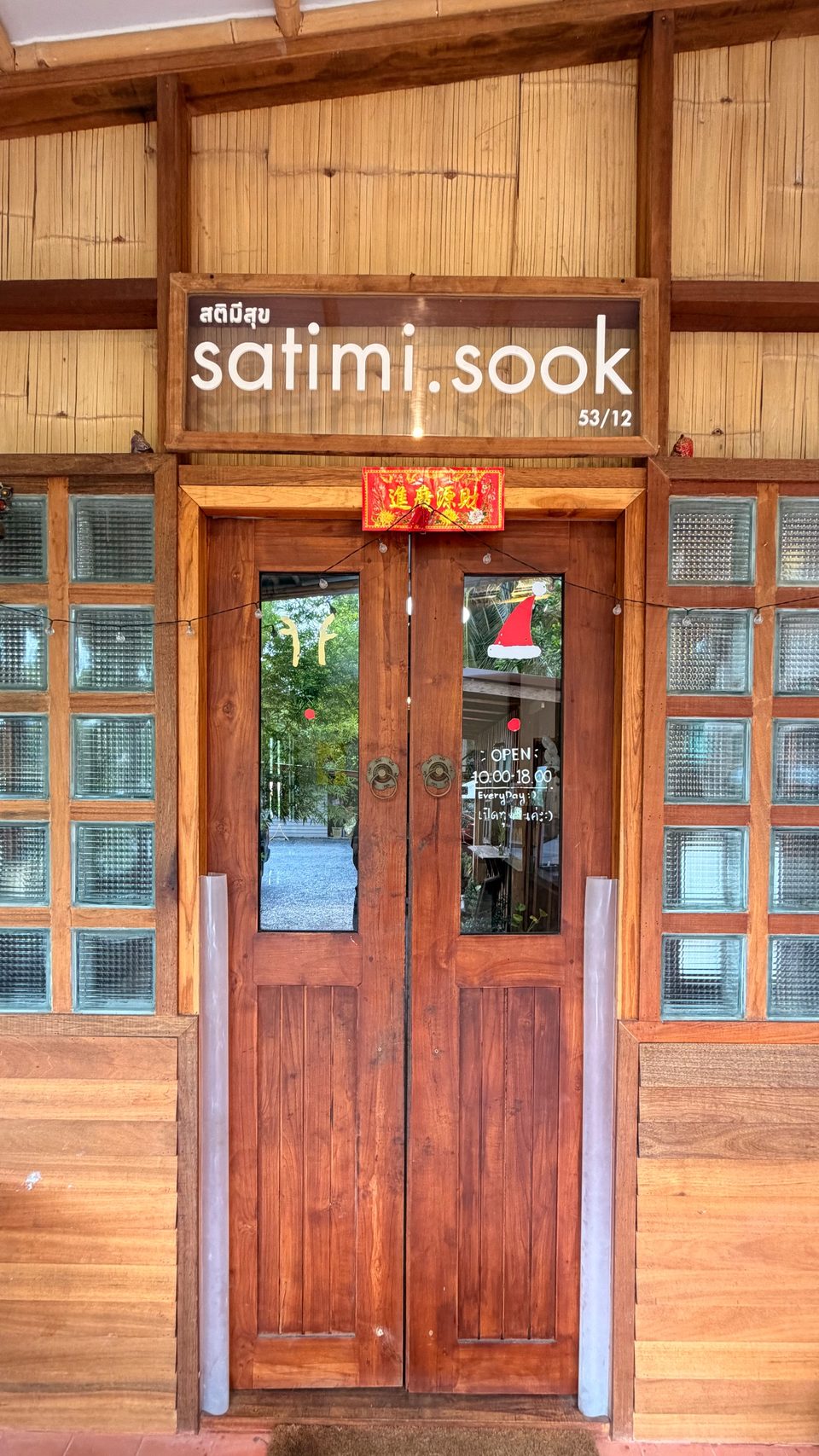 The wooden front doors of Satimi.Sook, with the shop name above them